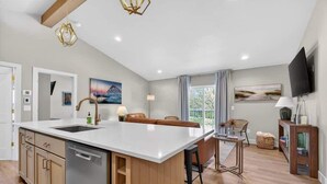 A modern kitchen with a large island, wooden cabinets, and a built-in dishwasher. - Sturgeon Bay Boat Condo w Marina Slip (Sturgeon Bay)