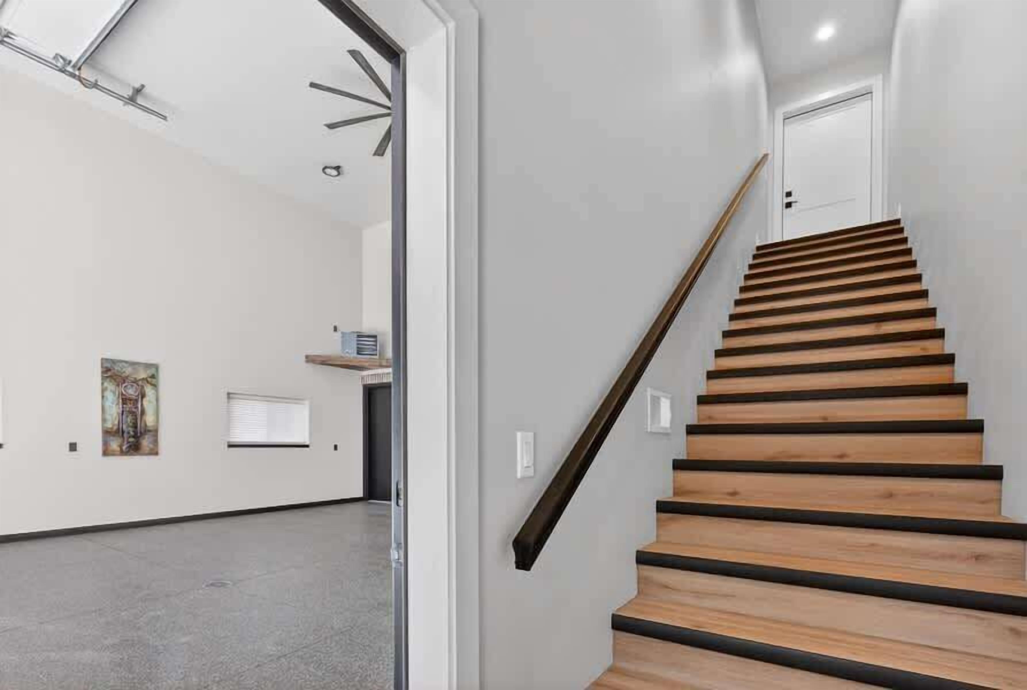 Un escalier avec des marches en bois et une rampe, menant à une porte située en haut.