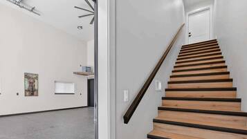 Un escalier avec des marches en bois et une rampe, menant à une porte située en haut.