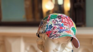A bust sculpture with a colorful hat and beaded necklace.