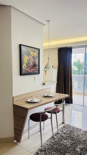 Un comedor moderno con una mesa de madera, dos sillas, una lámpara colgante y un cuadro enmarcado en la pared.