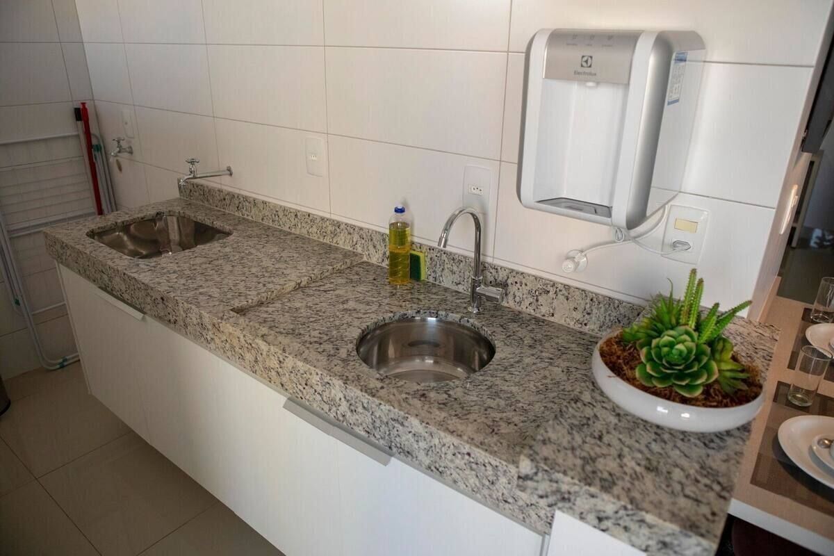 Una cocina con encimeras de granito, un lavamanos doble, dispensador de jabón y una planta en maceta.
