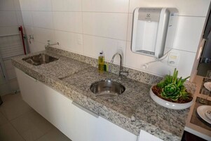Una cocina con encimeras de granito, un lavamanos doble, dispensador de jabón y una planta en maceta.