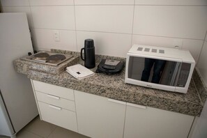 Una cocina con encimera de granito, cafetera, microondas y balanza.