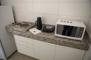Uma cozinha com bancada de granito, cafeteira, micro-ondas e balança.