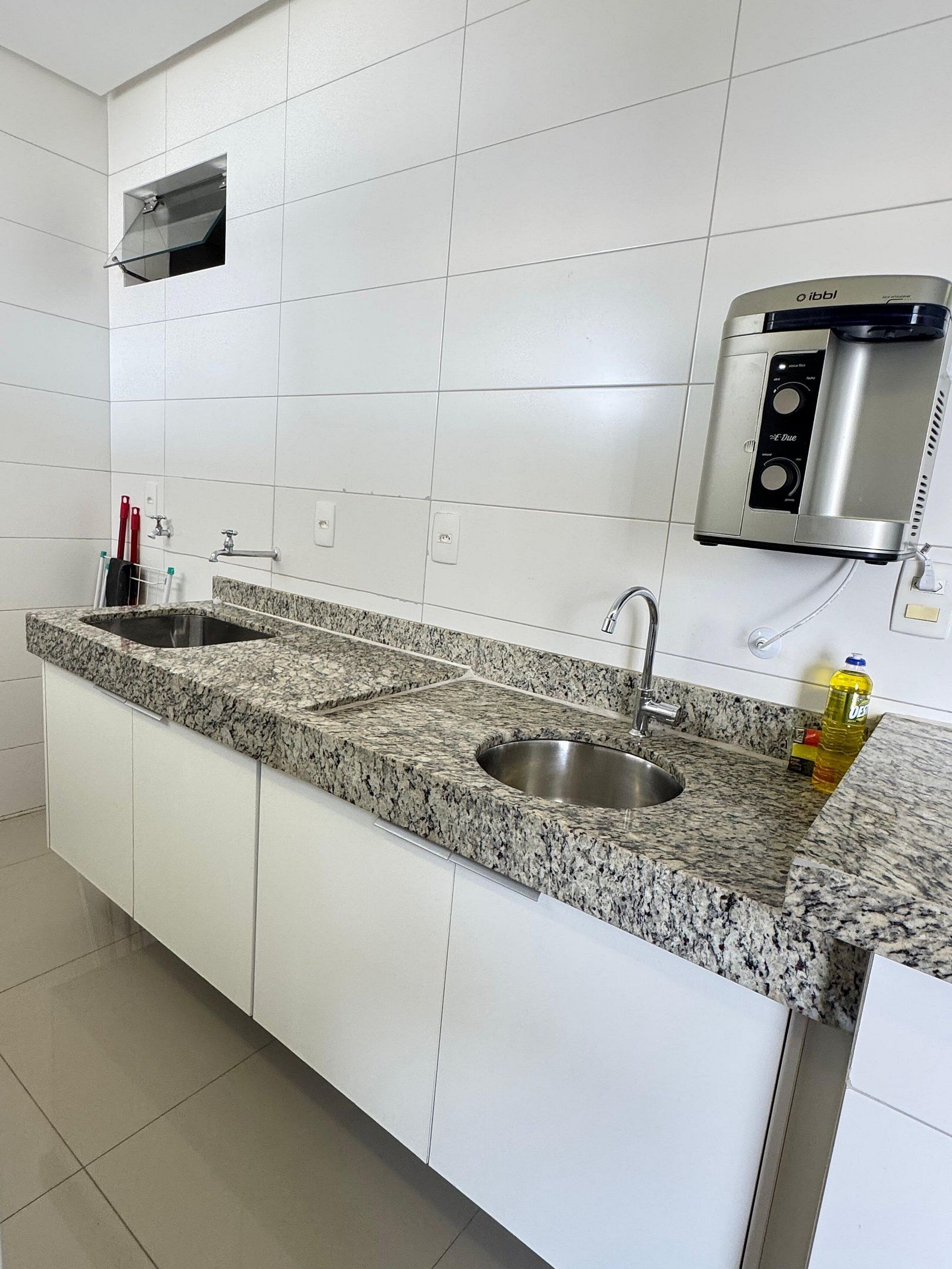 Una cucina con piani di lavoro in granito, lavelli in acciaio inox e macchina del caffè integrata.