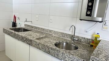 Una cucina con piani di lavoro in granito, lavelli in acciaio inox e macchina del caffè integrata.