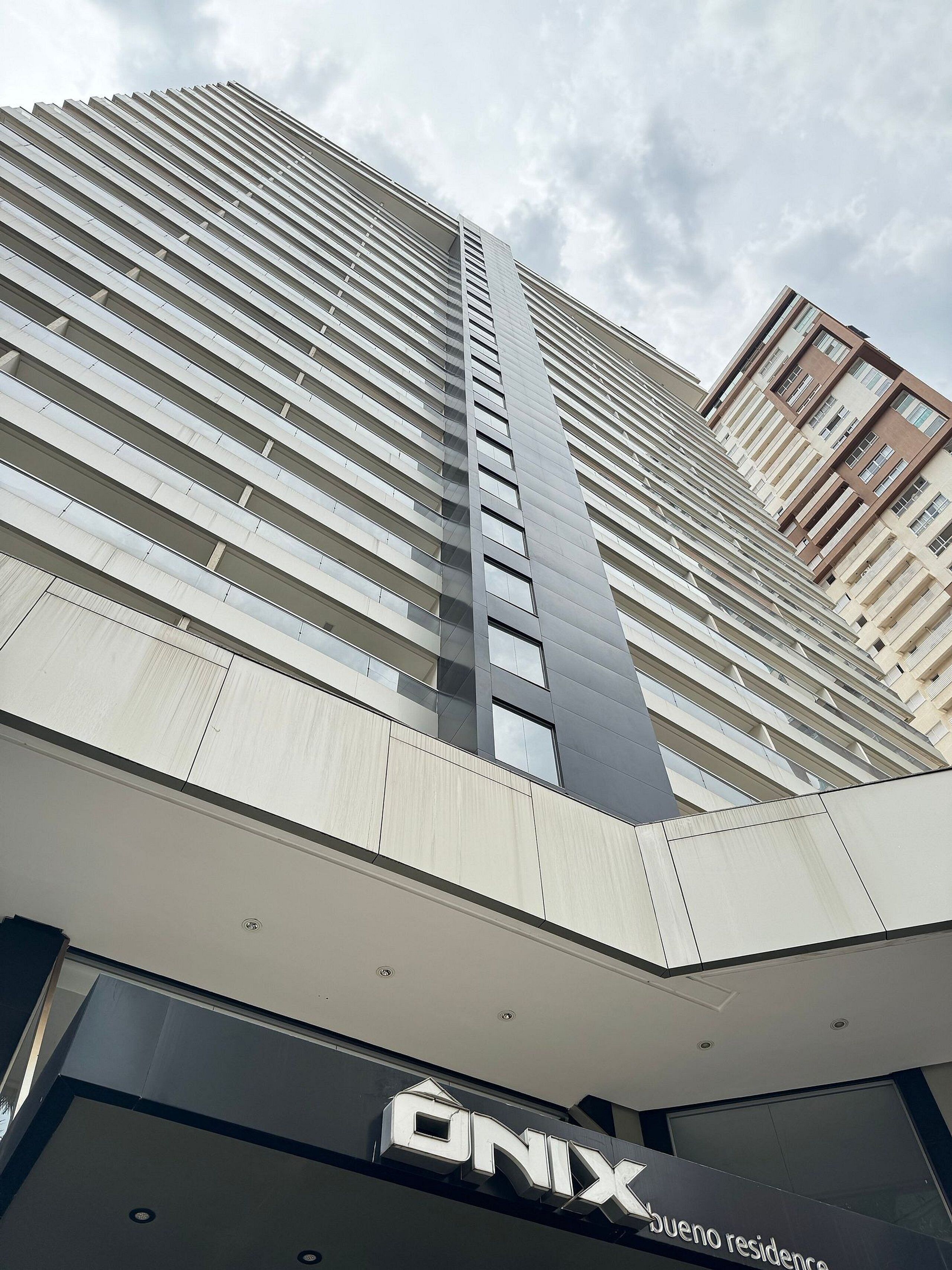 Un edificio de gran altura con un diseño arquitectónico moderno, que destaca por una línea vertical prominente y varios balcones.
