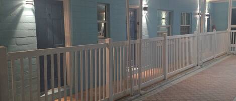 A building with a white fence, a covered walkway, and a tiled floor.