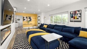 Ein modernes Wohnzimmer mit Sofa, Hocker und Kamin.