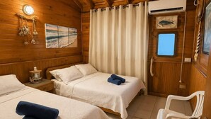 A cabin with two beds, a small table, a chair, a window, and a wall-mounted air conditioner. - La Casa del Ancla - A beautiful nautical cabin! (San andrés)