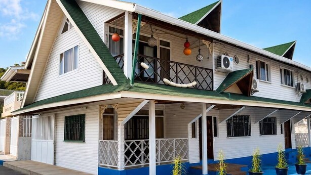 A two-story building with a balcony, air conditioning units, and potted plants. - La Casa del Ancla - A beautiful nautical cabin! (San andrés)
