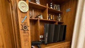 A wooden entertainment unit with a television, remote controls, and decorative items. - La Casa del Ancla - A beautiful nautical cabin! (San andrés)
