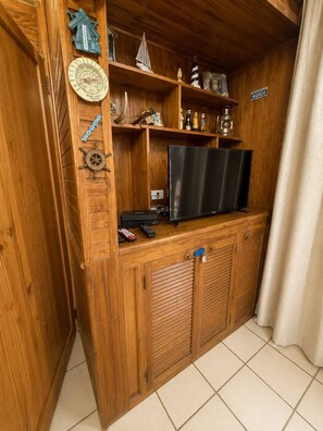 A wooden entertainment unit with a television, remote controls, and decorative items. - La Casa del Ancla - A beautiful nautical cabin! (San andrés)