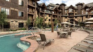 A hotel with a pool, outdoor seating, and multiple balconies. - Luxury 2BR-Sleeps 8! Near Gondola and Hiking-Hot Tubs, Spa, A/C-June 2027 (Breckenridge)