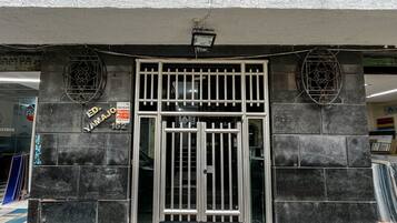 A building entrance with a metal gate, a sign with 'ED YAMAJO 162', and a tiled wall.