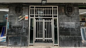 Entrada de un edificio con una reja metálica, un cartel que dice 'ED YAMAJO 162' y un muro de azulejos.