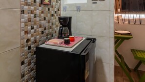 Una cocina con cafetera, un lavamanos pequeño y salpicadero de azulejos.