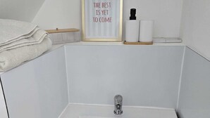 Ein Badezimmer mit einem weißen Waschbecken, einem Holzschrank und einem gerahmten Zitat zur Inspiration über dem Spiegel.