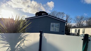 A residential area with a house number 20, a white fence, and a clear sky.