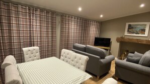 A dining area with a table and chairs, a sofa, and a television.
