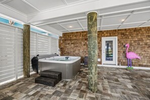A spa area with a hot tub, wooden flooring, and a decorative flamingo statue. - Driftwood Dunes | Brand New Oceanfront Beach House | Hot Tub | Elevator | EV Charger | Sleeps 17 (Fernandina Beach)
