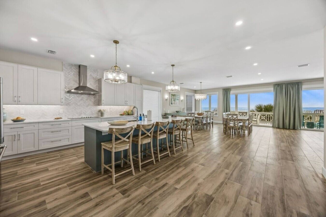 A spacious kitchen with a central island, wooden chairs, and a dining area with a view.