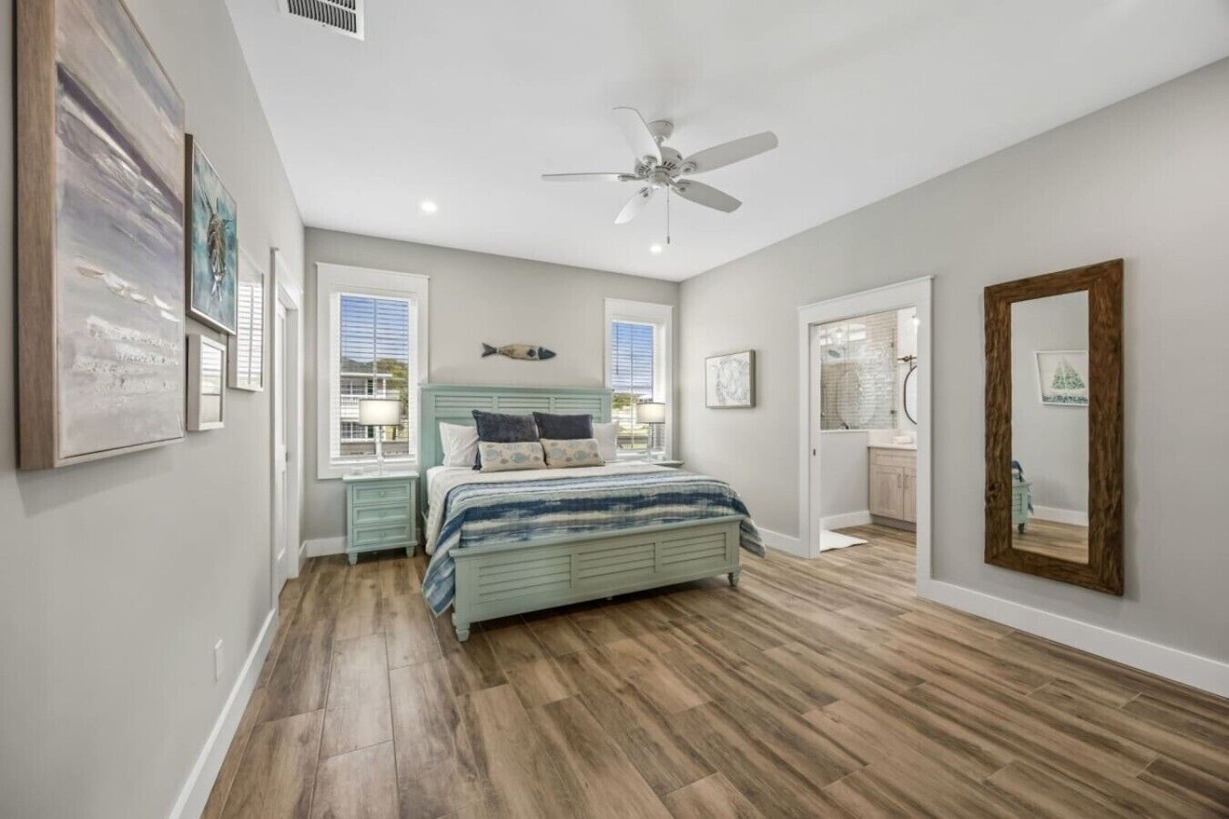 A bedroom with a bed, a ceiling fan, a fish decoration, and a large mirror.