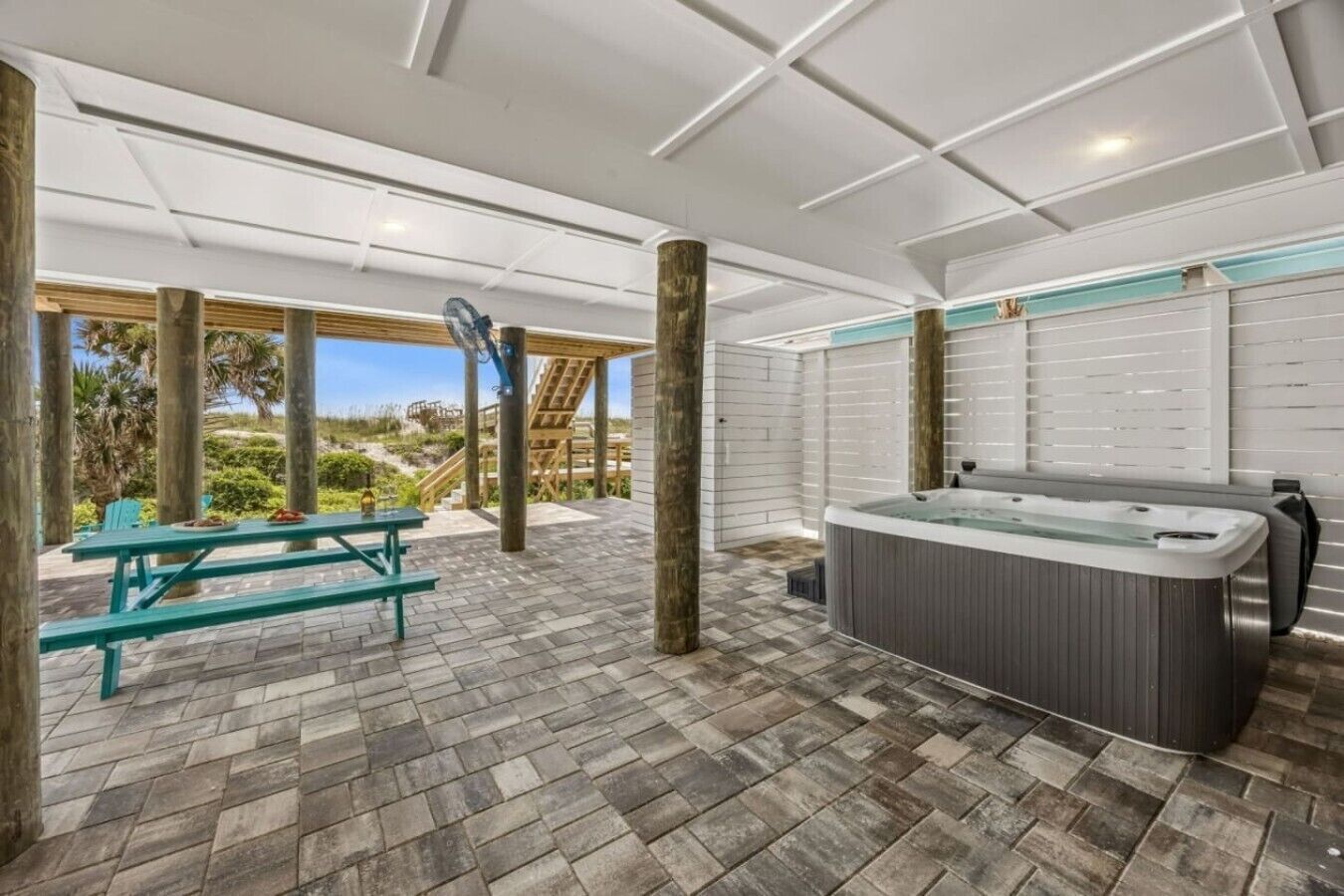 An outdoor patio area with a hot tub, picnic table, and wooden deck.