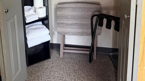 A walk-in closet with a hanging rod, shelves with towels, and a bench.
