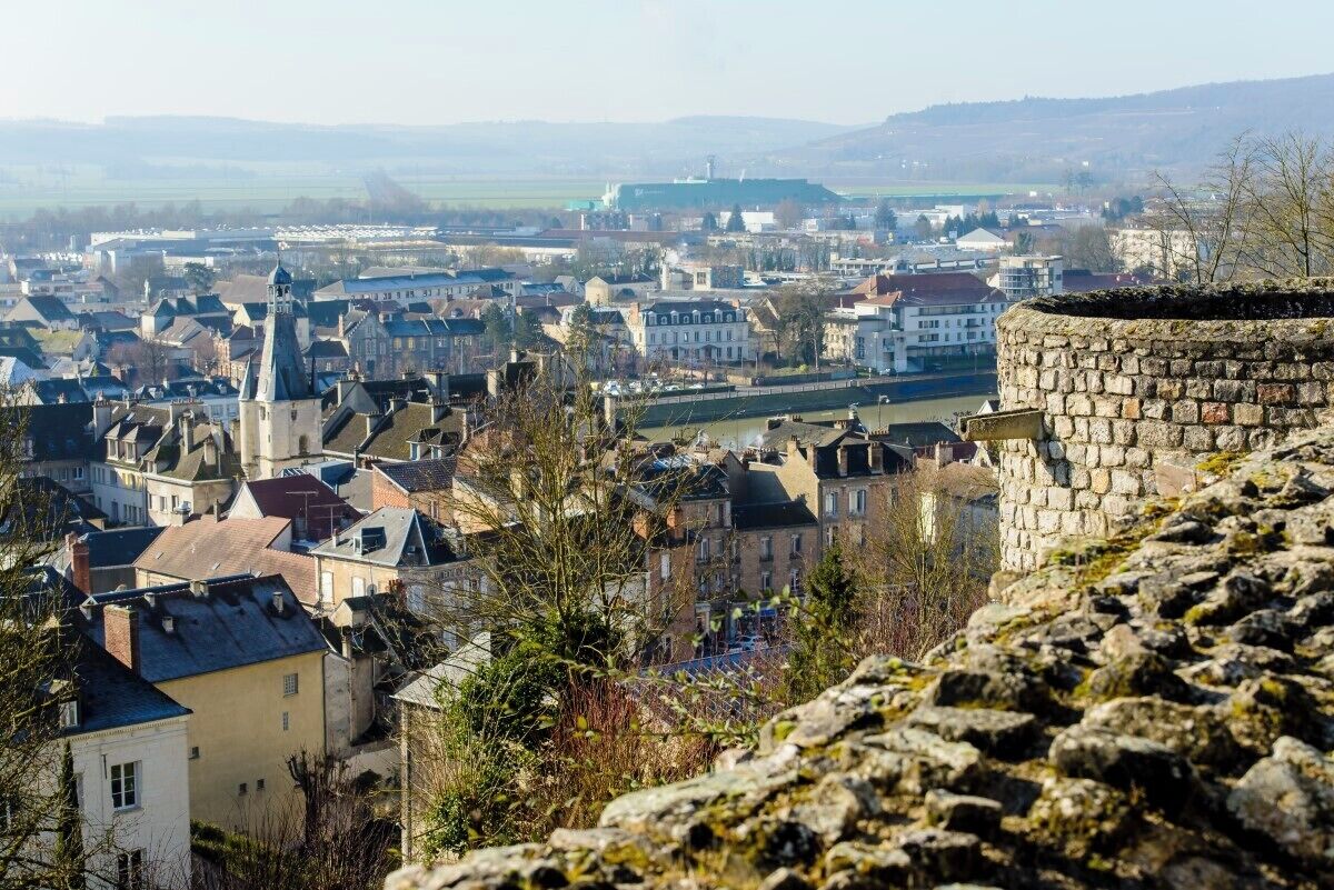 A town with historic stone walls, a river, and a mix of residential and commercial buildings.