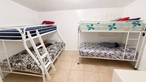 Una habitación con dos literas, techo blanco y suelo de baldosas.