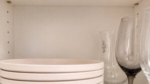Una pila de platos blancos y una copa de vino sobre una repisa.
