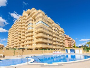 Ein mehrstöckiges Hotel mit Balkonen, einem Schwimmbad und einem strahlend blauen Himmel.