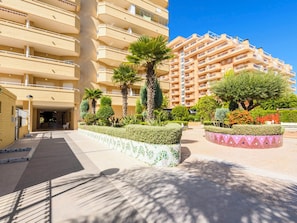 A multi-story residential building with balconies, a paved courtyard, and landscaped gardens. - Cala Blanca I by Interhome (Oropesa del Mar)