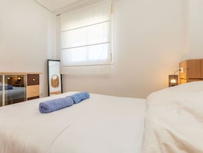 Ein Hotelzimmer mit einem Bett, einem Schreibtisch, einem Spiegel, einem Vorhangfenster und einer Nachttischlampe.