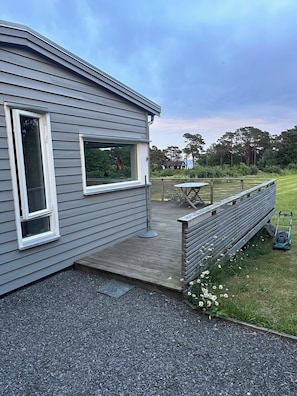 A house with a patio, a lawn, and a view of trees. - A large cabin on the outskirts of Tromøya, with Raet National Park as its closest neighbor. (Agder)