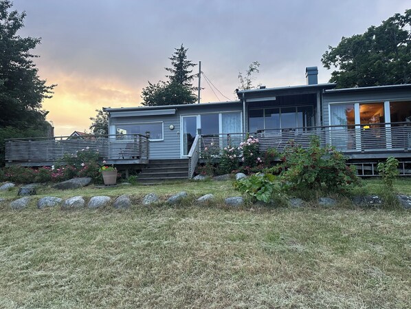 A single-story house with a deck, a front door, and a staircase leading to a second level.