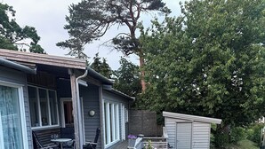 A wooden deck with a potted plant, a bench, and a small table. - A large cabin on the outskirts of Tromøya, with Raet National Park as its closest neighbor. (Agder)