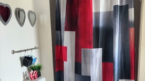 Ein Badezimmer mit Duschvorhang, Toilette, Waschbecken und einer kleinen Pflanze auf der Ablagefläche.