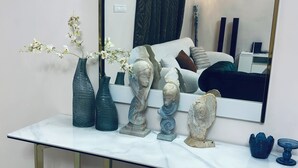 A marble console table with gold legs, flanked by two glass vases and three sculptural items. A mirror reflects a bed and curtains. - Cozy apartment with a large terrace (Libreville)