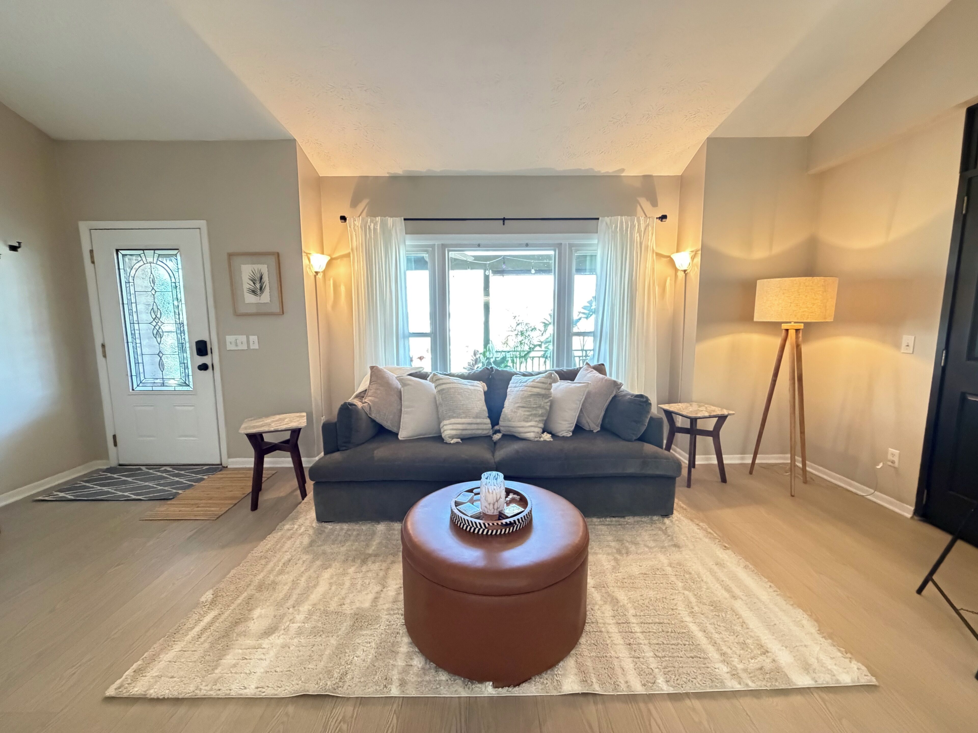 Ein Wohnzimmer mit Sofa, Hocker und Lampe.