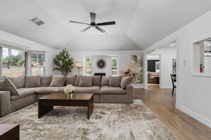 A spacious living room with a sectional sofa, a coffee table, a ceiling fan, and large windows. - Yosemite 25 Min · Hot Tub · Game Room · Sleeps 8 (Oakhurst)