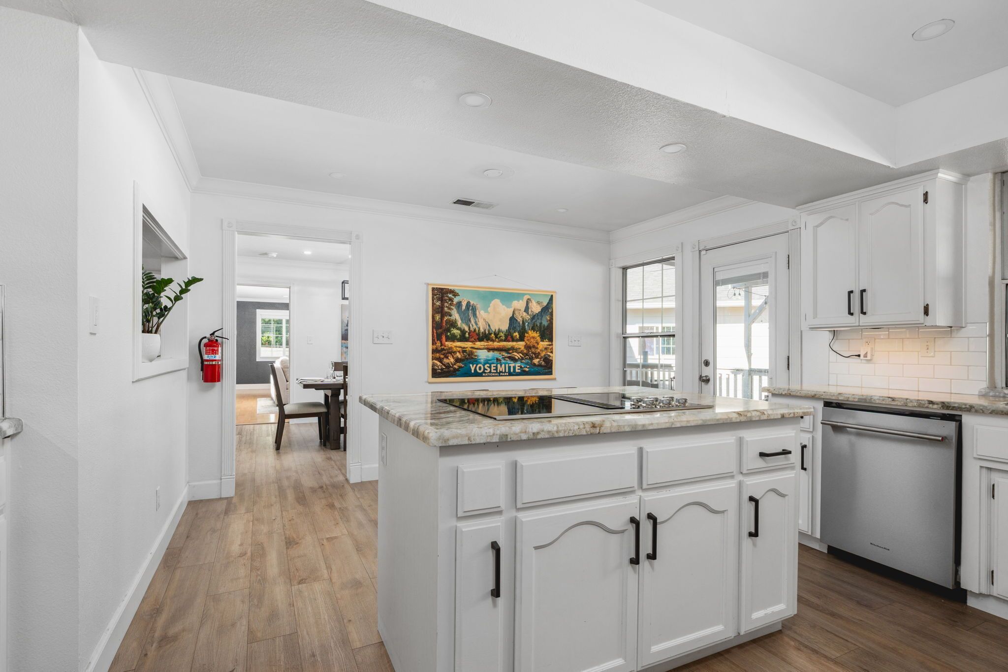 A modern kitchen with white cabinetry, a central island, and a painting above the sink.
