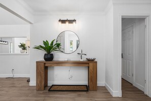 Une salle de bain moderne avec une console en bois, un miroir rond, une plante en pot et un luminaire.