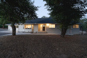 A single-story house with a front porch, a garage, and a small driveway. - Yosemite 25 Min · Hot Tub · Game Room · Sleeps 8 (Oakhurst)