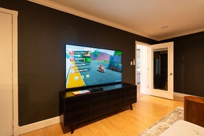 A television mounted on a wall displaying a racing game. - Yosemite 25 Min · Hot Tub · Game Room · Sleeps 8 (Oakhurst)