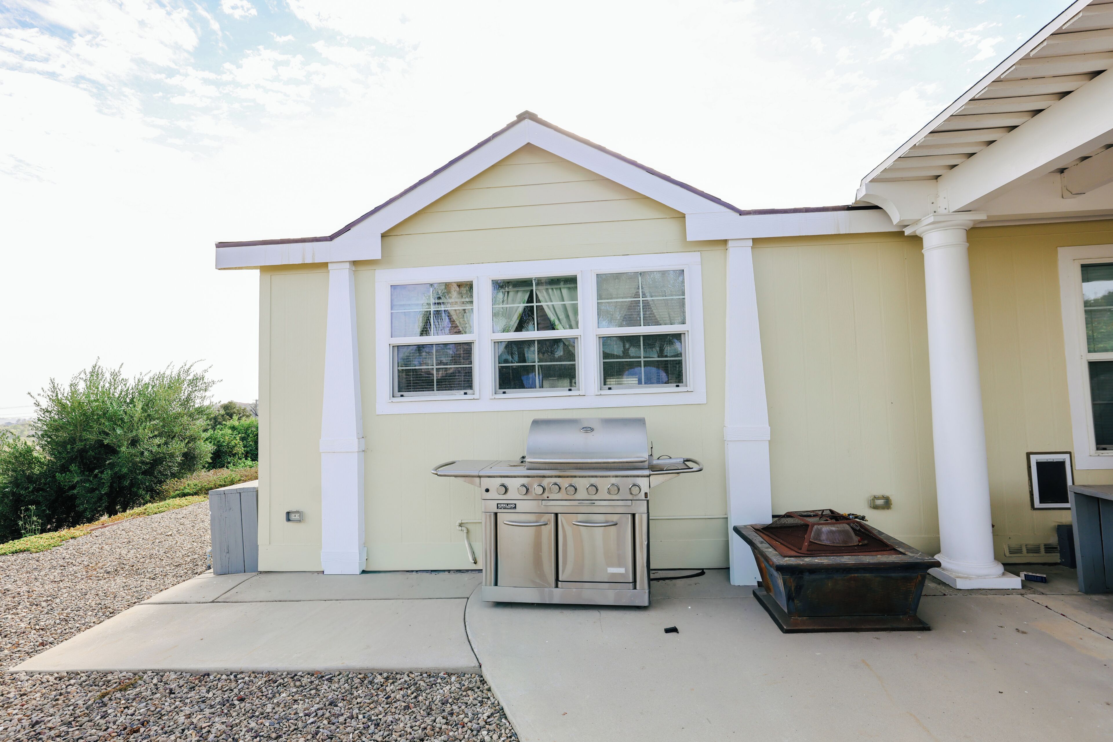 A house with a built-in outdoor grill, a window, and a small shed.