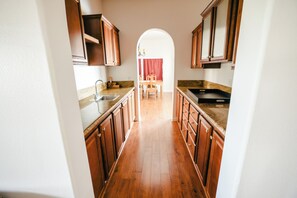 A narrow kitchen with wooden cabinets and a central island. - Spacious Orchard Retreat with Golf Course Views & Large Patio (Moorpark)