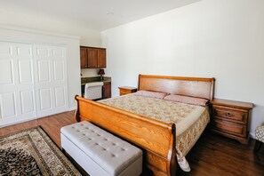 A bedroom with a wooden bed, a nightstand, a bench, and a wardrobe. - Spacious Orchard Retreat with Golf Course Views & Large Patio (Moorpark)